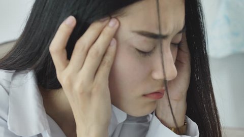 Asian woman feeling stress from work in the office.Tired business woman at workplace in office holding his head on hands feel headache.