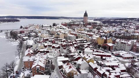 Reverse drone footage revealing a beautiful windmill with a colorful houses and the old cathedral of Strängnäs in the background. Filmed in realtime at 4k.