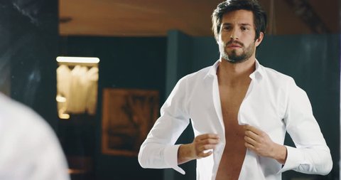Slow motion of handsome young man is dressing a white shirt for going to work in his bedroom.