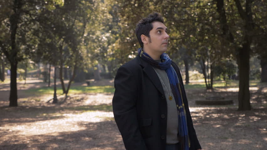 Carefree,freedom.Young man standing in the park opening arms,looking up