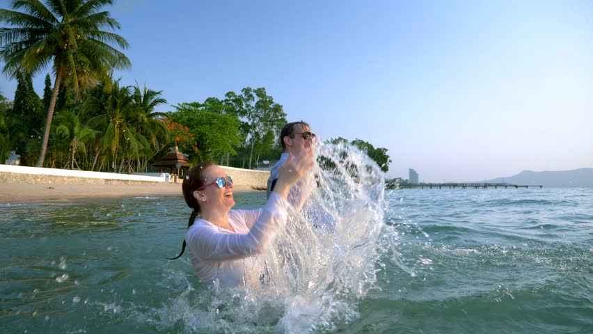 happy couple business woman and businessman in suit and sunglasses splashing into the sea at luxury resorts. The concept of a long-awaited vacation, freelancing.