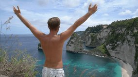 Man enjoying freedom in tropical paradise on top of idyllic beach - young male stands arms wide open above dreamlike beach- Beautiful nature in Indonesia 