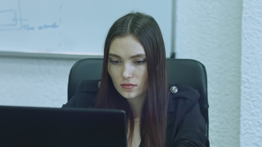 Attractive young woman using computer at her working place. Office worker is concentrated doing her job.