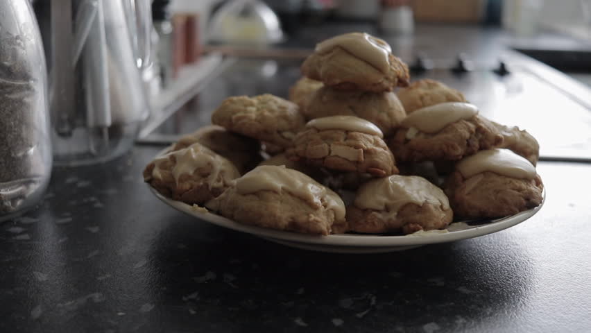 Slow pan left to right of plate of stacked glazed chocolate and almond cookies.