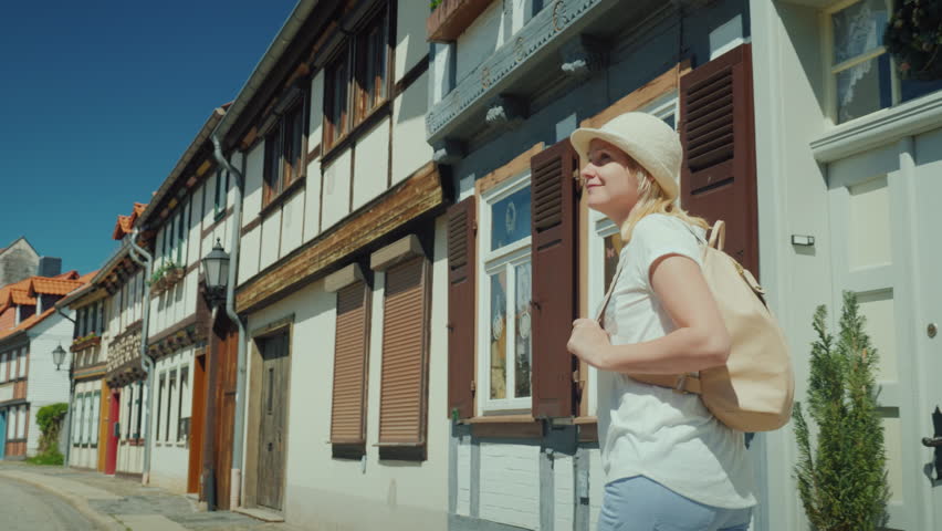 Rear view: A woman tourist enjoys a walk along the beautiful deserted street of the city.
