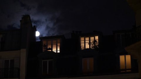 Beautiful full moon over Parisian Hausmannian building on Champs-Elysees at night with beautiful mansard roof illuminated balconies logia windows 4K UHD footage for film and series
