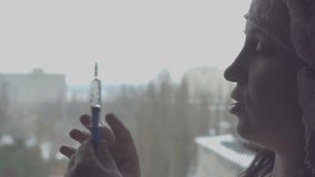 A young woman holding a medical syringe. On anybody protective cap. Medicinal solution. Treating illness. Room in the house. Human health. Nurse. Veterinarian. 4K video