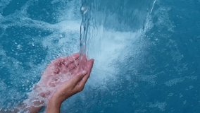 woman hands under the waterfall in the pool in slow motion