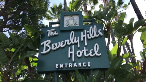 LOS ANGELES, March 30th, 2019: Low angle steady shot of the Beverly Hills Hotel entrance sign on Sunset Boulevard, surrounded by palms. The iconic hotel is owned by the Sultan of Brunei.