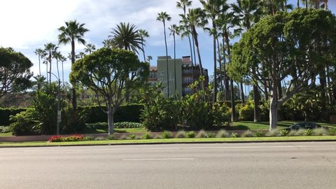 LOS ANGELES, March 30th, 2019: Exterior wide shot of the Beverly Hills Hotel, with blue sky and palms, with traffic passing by on Sunset Boulevard. The iconic hotel is owned by the Sultan of Brunei.