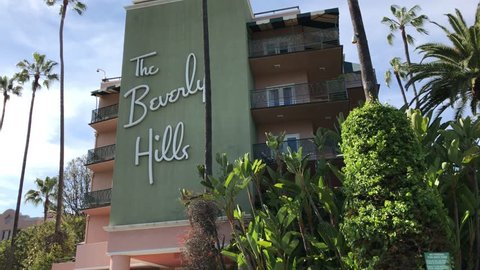 LOS ANGELES, March 30, 2019: Low angle close up shot of the Beverly Hills Hotel facade, surrounded by palms and a blue sky, then pan down to driveway. The iconic hotel is owned by the Sultan of Brunei