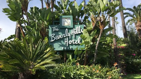 LOS ANGELES, March 30, 2019: Steady shot of the Beverly Hills Hotel sign on Sunset Boulevard on a sunny day, surrounded by palms and a blue sky, then pan to street. The Sultan of Brunei owns the hotel