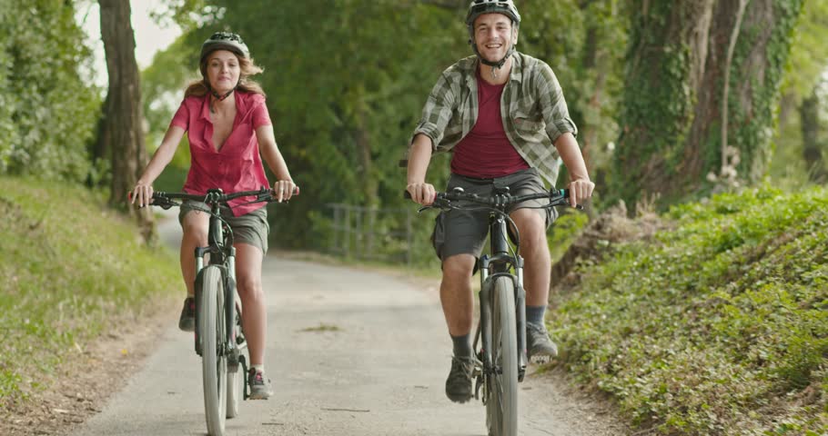 Romantic active couple riding e-bike bicycles on a beautiful outdoor woods path. Wide shot. Friends italian trip in Umbria. 4k slow motion Royalty-Free Stock Footage #1026953621