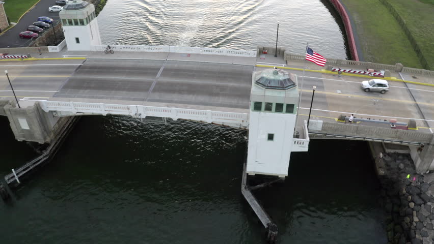 Aerial drone shot at over a bridge and a small white boat heading out into the Atlantic Ocean off the coast of Belmar, New Jersey.