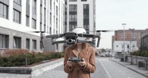 Beautiful young woman in modern virtual reality glasses controlling flying drone. Pretty girl using vr glasses and smartphone to control the quadcopter. Female travel blogger use unmanned copter