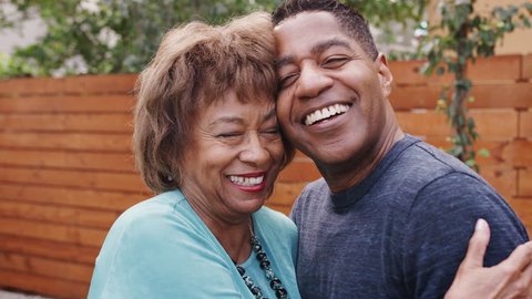 Happy senior African American woman and her middle aged son embracing, head and shoulders, close up