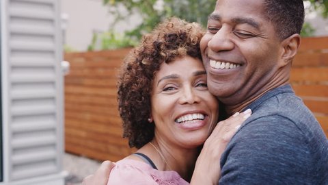 Happy middle aged African American couple talking and embracing outdoors, close up