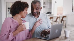Senior African American man and his middle aged daughter using a laptop and laughing together at home, close up - Powered by Shutterstock - Get 15% off with code: PIKWIZARD15
