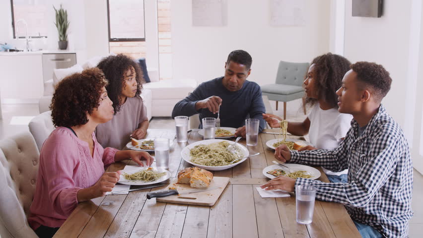Elevated view of an African American family sitting at dinner table talking as they eat together, close up