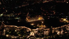 Aerial drone night video of iconic illuminated landmark Acropolis hill and the Masterpiece of Ancient times and Western civilisation - the Parthenon, Athens historic centre, Attica, Greece