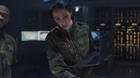 Diverse Team of Military Personnel Have Meeting in Top Secret Facility, Female Leader Holds Laptop Computer Talks with Male Specialist. People in Uniform on Strategic Army Meeting