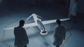 Two Aerospace Engineers Work On Unmanned Aerial Vehicle / Drone Prototype. Aviation Experts in White Coats Talking, Using Tablet Computer. Industrial Laboratory with Surveillance or Military Aircraft - Powered by Shutterstock - Get 15% off with code: PIKWIZARD15