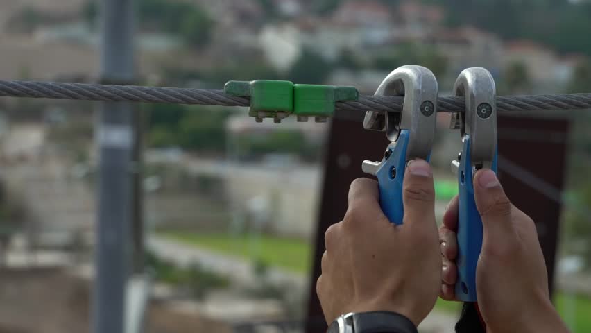 Visitor of a high rope course uses carabiner for safety reasons