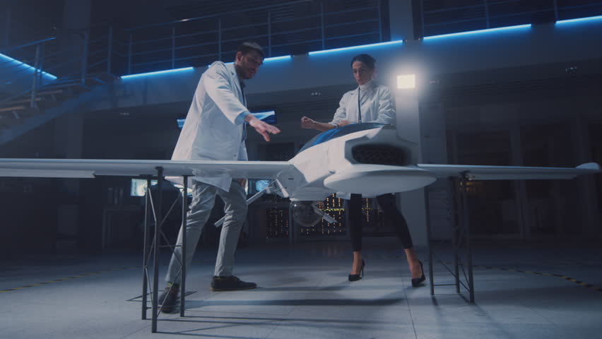 Meeting of Aerospace Engineers Working On Unmanned Aerial Vehicle / Drone Prototype. Aviation Scientists in White Coats Talking. Commercial Aerial Surveillance Aircraft in Industrial Laboratory Royalty-Free Stock Footage #1026993107