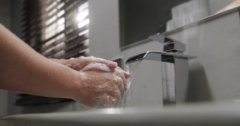 Young people and body care. Person rinsing hands in modern design bathroom at home. Man washing male hand with soap and water under faucet in hotel room during travel. Slow motion