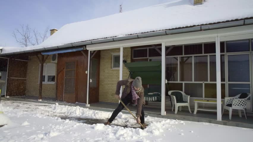 man cleaning shovelling fresh snow in yard slow motion
