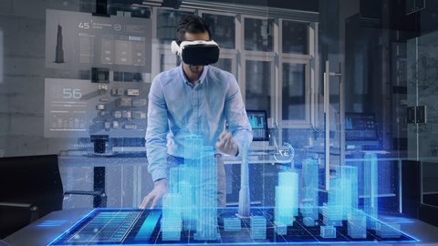 Professional Male Architect wearing Augmented Reality Headset makes gestures and redesigns 3D City Model. High Tech Office use Virtual Reality Modeling Software Application.