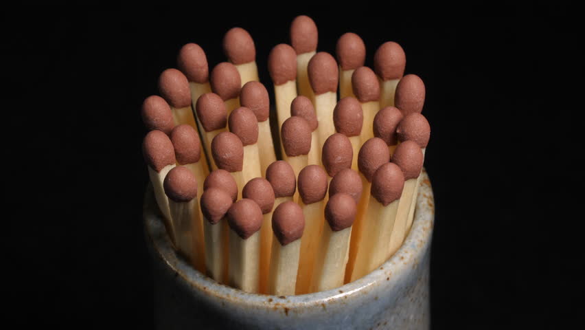 Pot of safety matches rotating on black background.