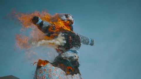 Burn doll on Shrovetide. Russian holiday Maslenitsa. Burning small doll on bonfire. Blue doll burns in slow motion.