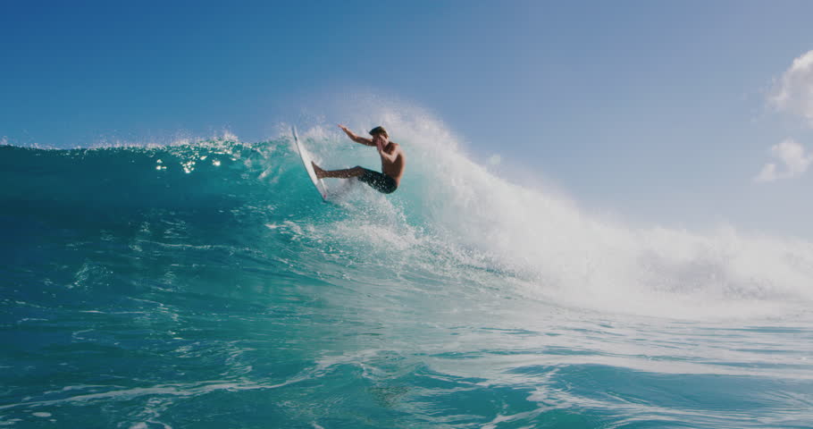 Surfer riding and turning with spray on blue ocean wave, surfing ocean lifestyle, extreme sports, slow motion