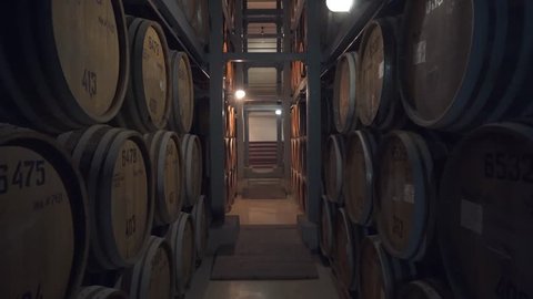 Barrels of cognac, wine or whiskey. Extract of brandy in oak barrels. Alcohol warehouse. Hundreds of barrels in an underground vault. Camera movement between barrels.