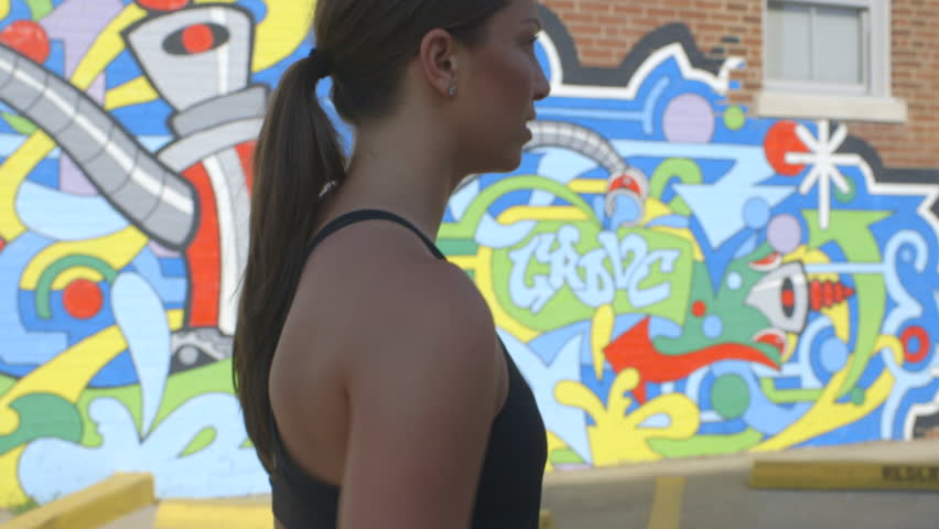 Cute fit girl walks past a wall of graffiti in St. Louis