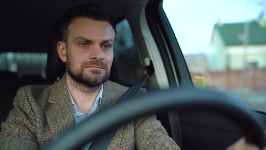 Satisfied bearded man driving a car down the street in sunny weather | Shutterstock HD Video #1027022351