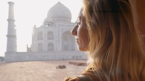 Girl loving the Taj Mahal in India making a heart with hands- Young woman makes heart shape finger frame over the temple in India enjoys travel and discovery 