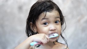 Dental hygiene. Asian cute girl or kid brushing her teeth by toothbrush in the bathroom. Healthcare concept. Slow motion video