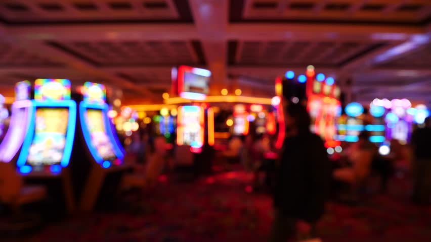 People walking in a brightly lit shopping arcade casino at night passing in front of the lens Royalty-Free Stock Footage #1027026263