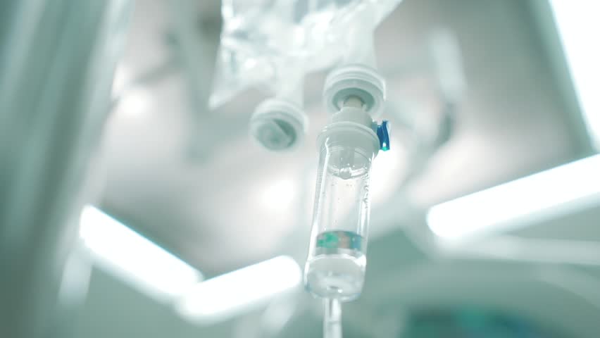 Intravenous drip in focus,surgeons team performing operation in the background,out of focus,infusion dripping. Royalty-Free Stock Footage #1027040678