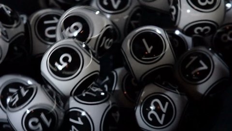 Black and white lottery balls in a bingo machine. Lottery balls in a sphere in motion. Gambling machine and euqipment. Slow motion.