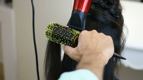 Hairdresser drying long black hair of in beauty saloon