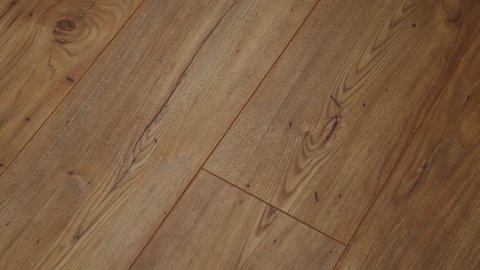 The camera moves along the floor, covered with laminated parquet with a brown wooden texture