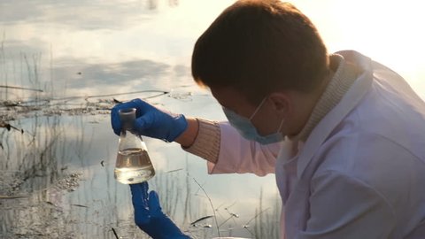 Biochemist takes a sample of water from the local dirty pond close up