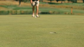 close look of hole set up of putt and wide miss. A steady close up clip showing a man hitting golf ball and the ball is missing the hole on a green grassy field.