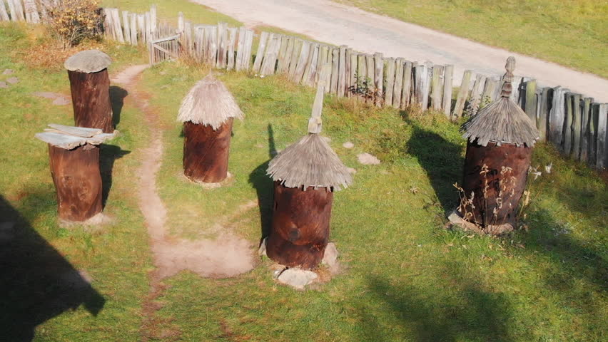 Old fashioned bee boxes. hewn from hollowed out logs. arranged in a fenced yard at an educational cultural village in Ukraine.