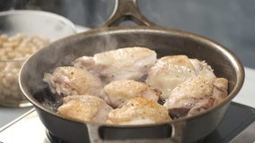 Cooking chicken raw pieces on hot iron pan by chef hands. Food concept video footage for recipe.