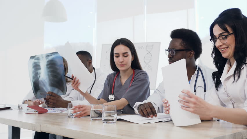 Team of multiethnic young doctors having a meeting in conference room in the modern hospital. Group of multiethnic doctors are medical studying studying disease histories patients, 4k