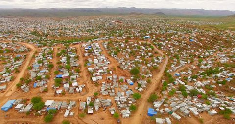 Fragile houses within harsh weather conditions and deserted terrain. Aerial 4K view of typical architecture in sub-Saharan Africa.